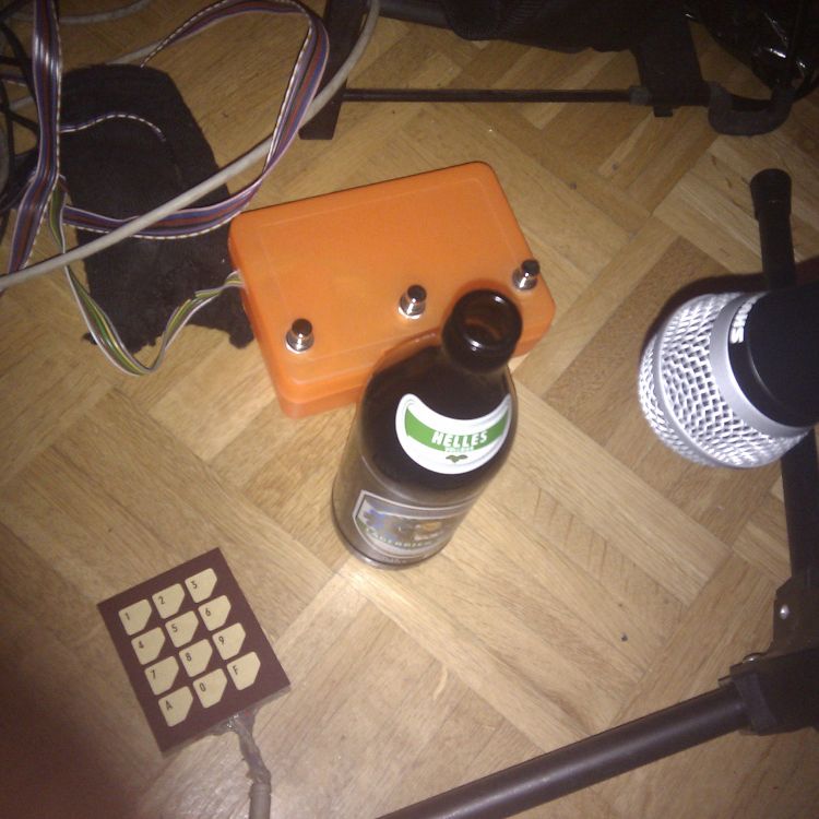 Bierflasche am Boden neben Mikrophon und selbstgebautem Fußcontroller in Plastikdose